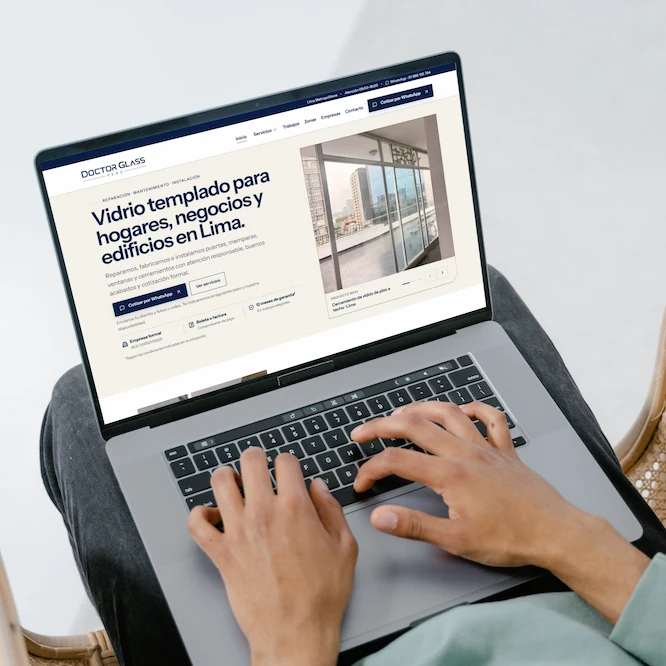 Overhead view of someone typing on a laptop showing the Doctor Glass tempered glass website in Spanish