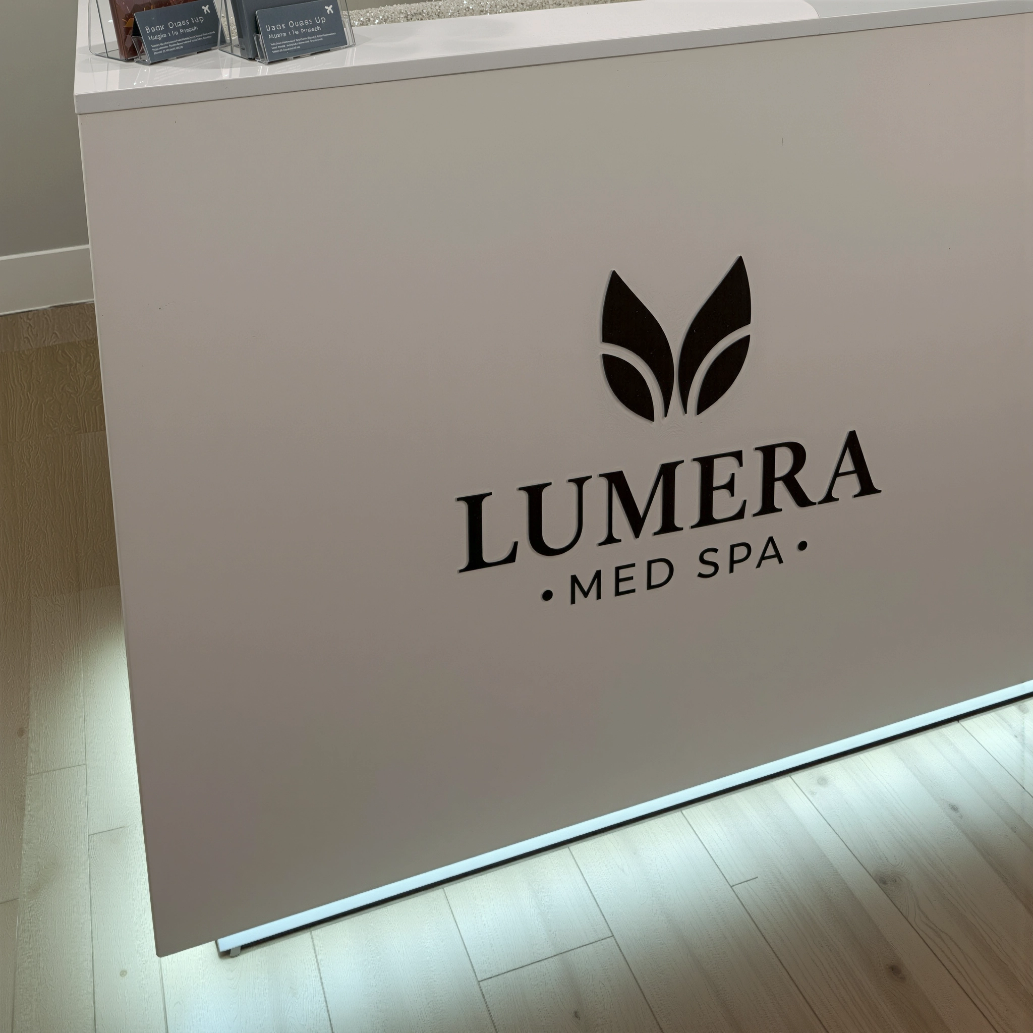 Close-up of Lumera Med Spa logo on a white reception desk